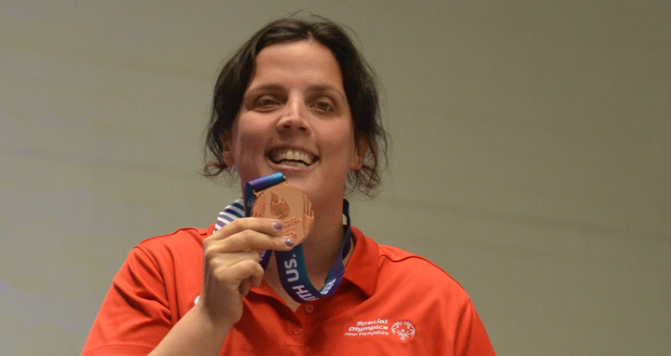 Athlete proudly smiling while holding up a medal